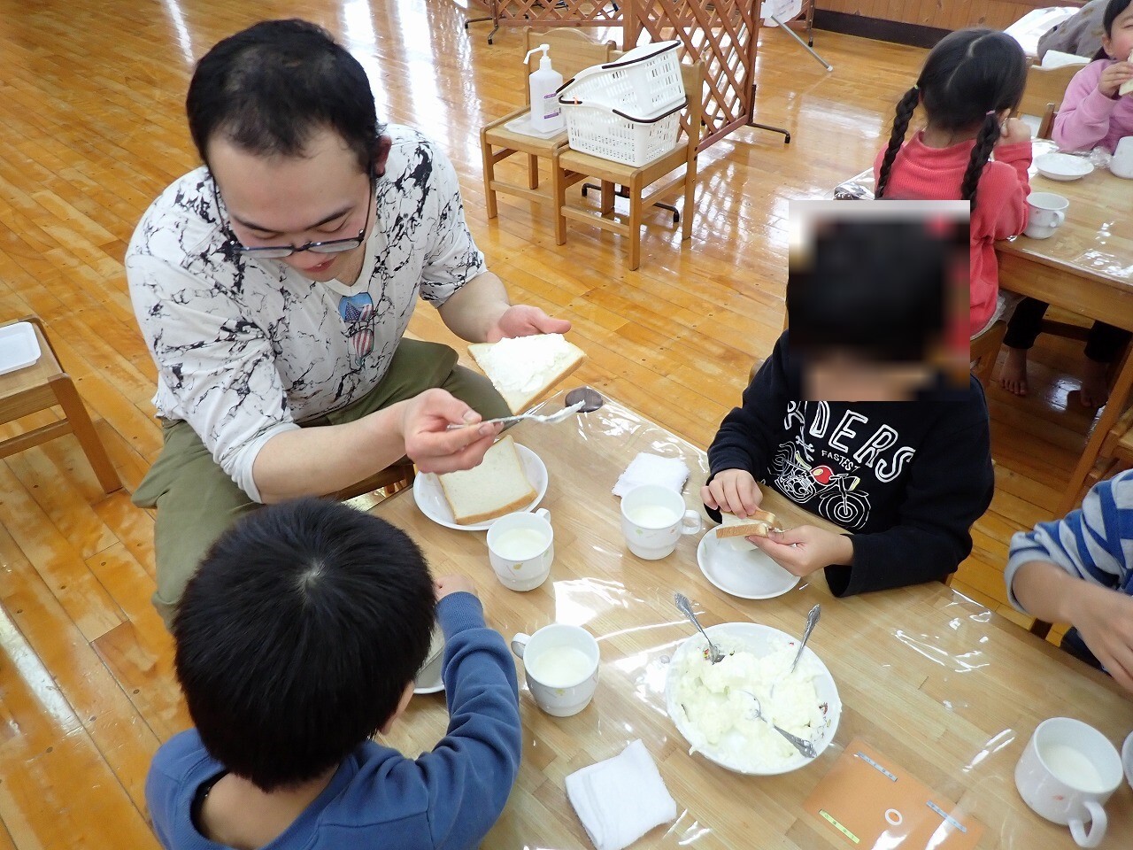 作ったバターを子どもたちと食べる青年